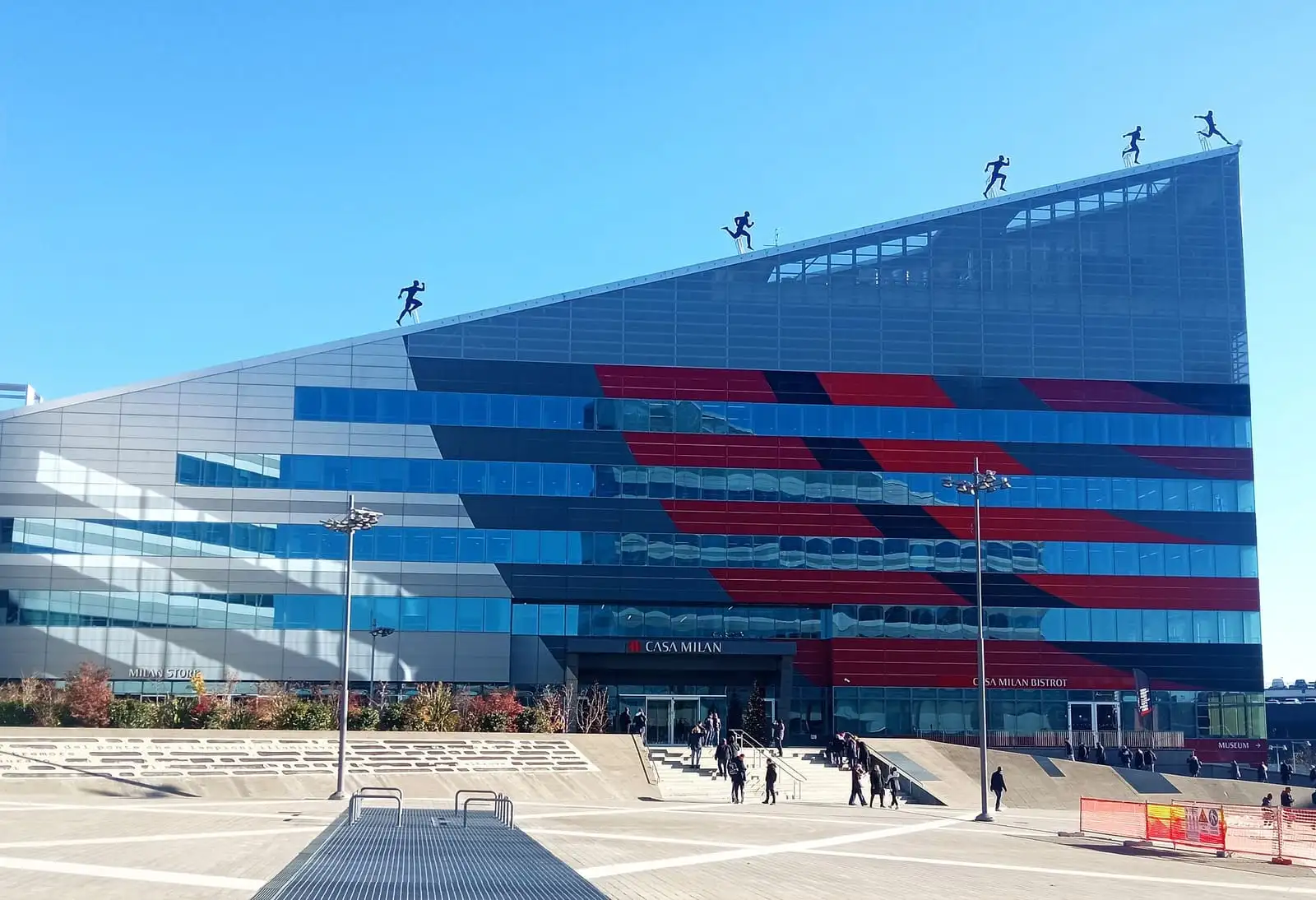 The glass front of Casa Milan, AC Milan's headquarters, striped red and black with player silhouettes on the roofline