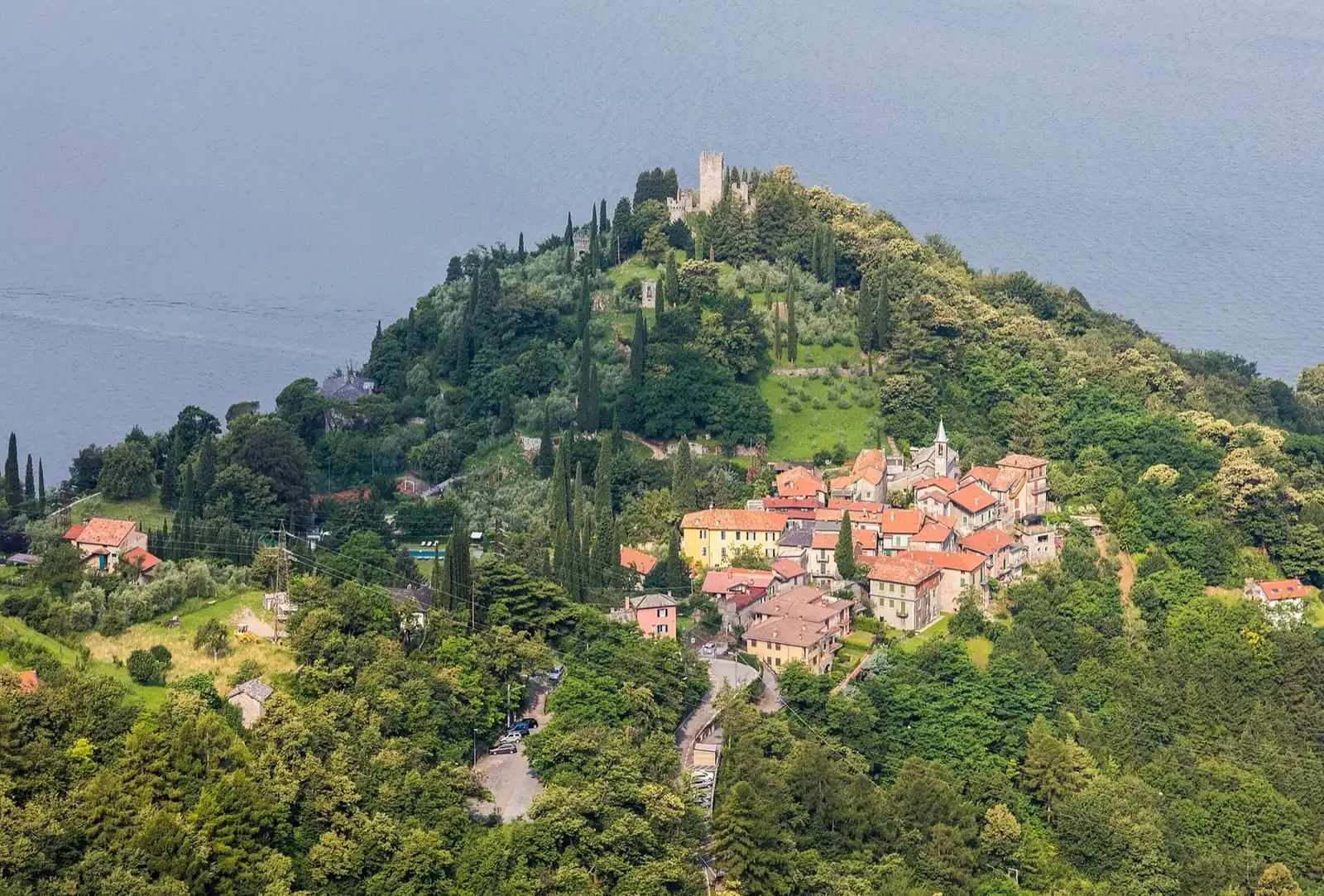 Castello di Vezio tower on a wooded hill above the village of Vezio and Lake Como