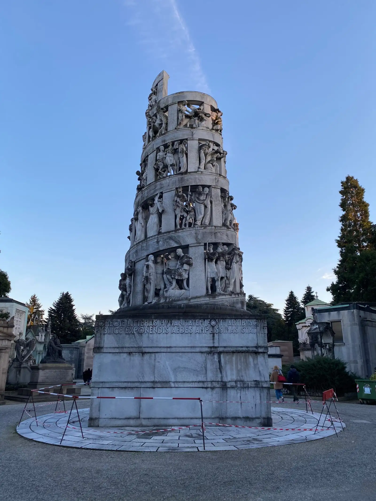 A carved column monument among the tombs of the Cimitero Monumentale