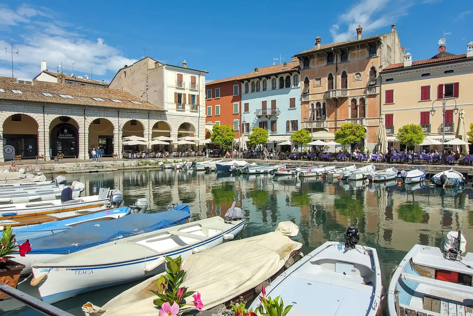 Small boats in the old harbor of Desenzano del Garda, lined with colorful buildings