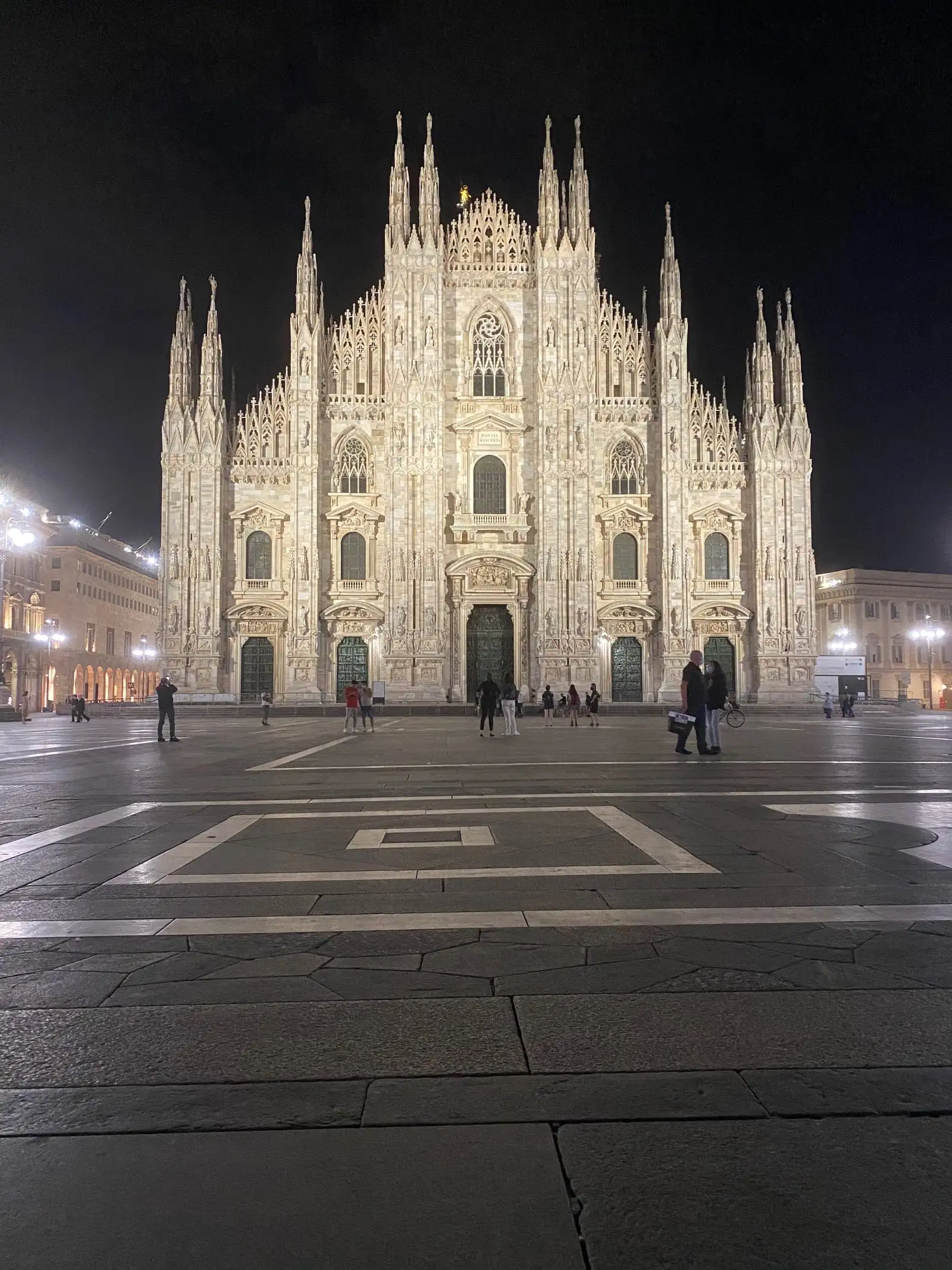 The Duomo facade lit up at night above an almost empty Piazza del Duomo