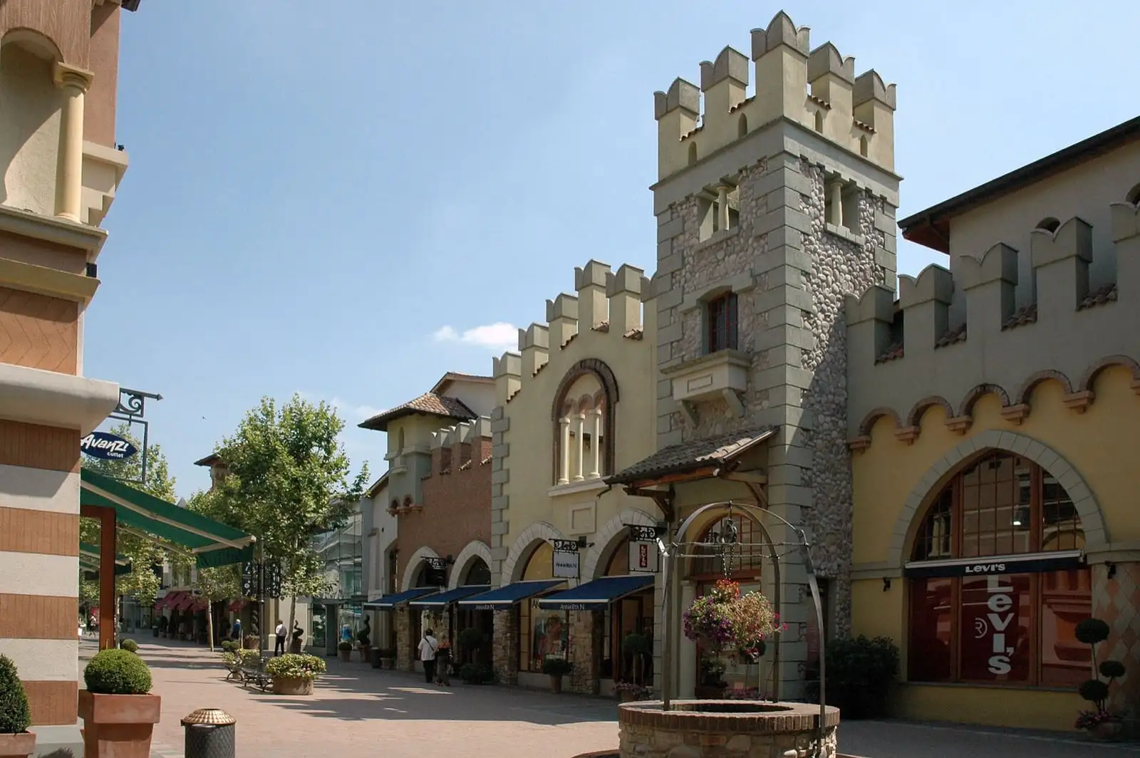 A street of Fidenza Village with crenellated towers and shop fronts in pastel colours