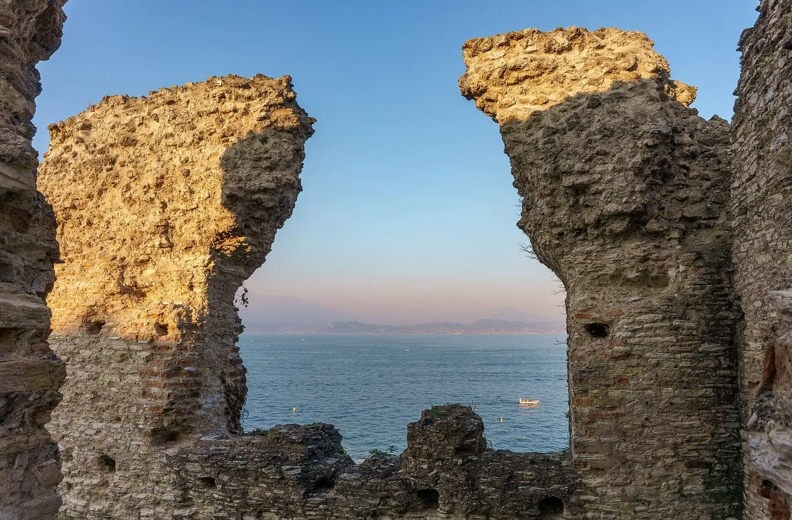 Ruined Roman walls at the Grotte di Catullo framing a view of Lake Garda