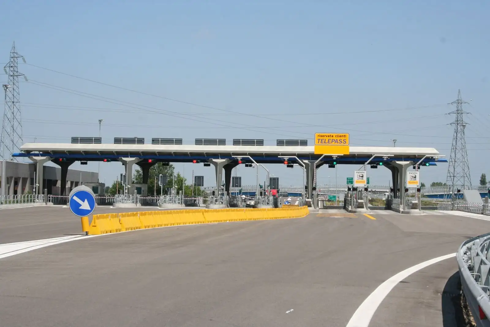 Italian motorway toll plaza with a yellow sign marking the lanes reserved for Telepass customers