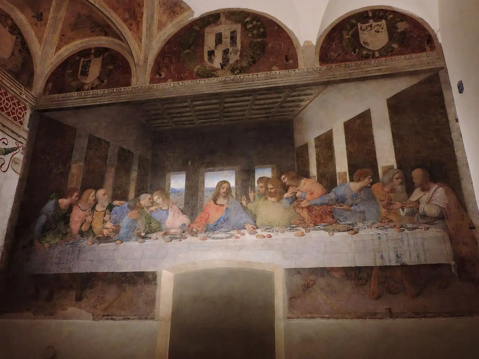 The Last Supper on the end wall of the refectory at Santa Maria delle Grazie, under three painted lunettes
