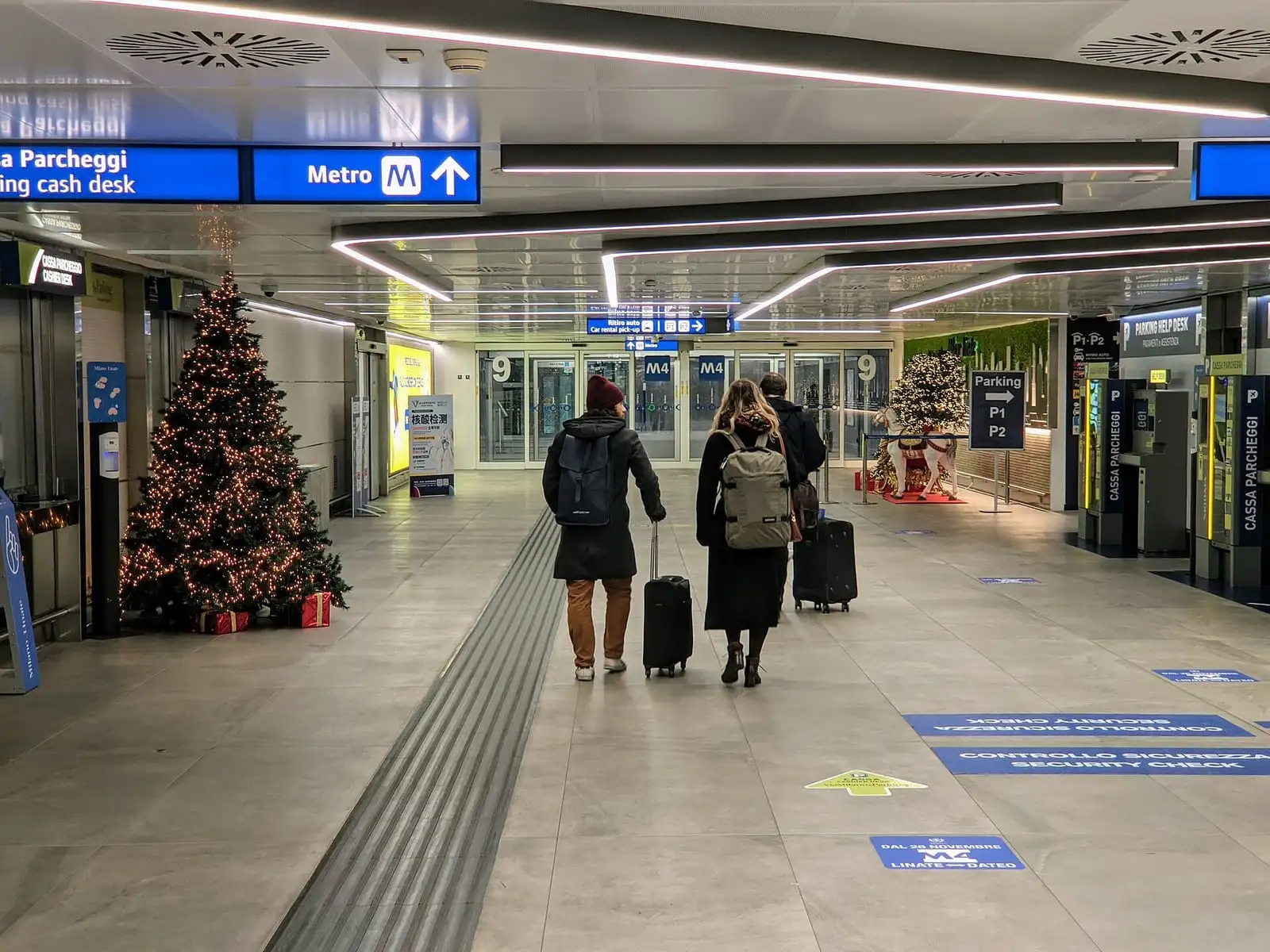 Walkway from the Linate Airport terminal to the M4 metro, with Metro M4 signs overhead