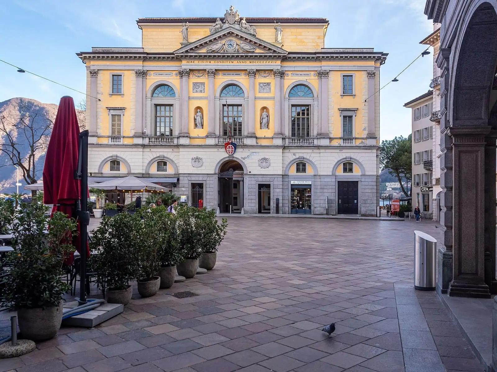 Piazza della Riforma in Lugano with the yellow neoclassical town hall and mountains behind