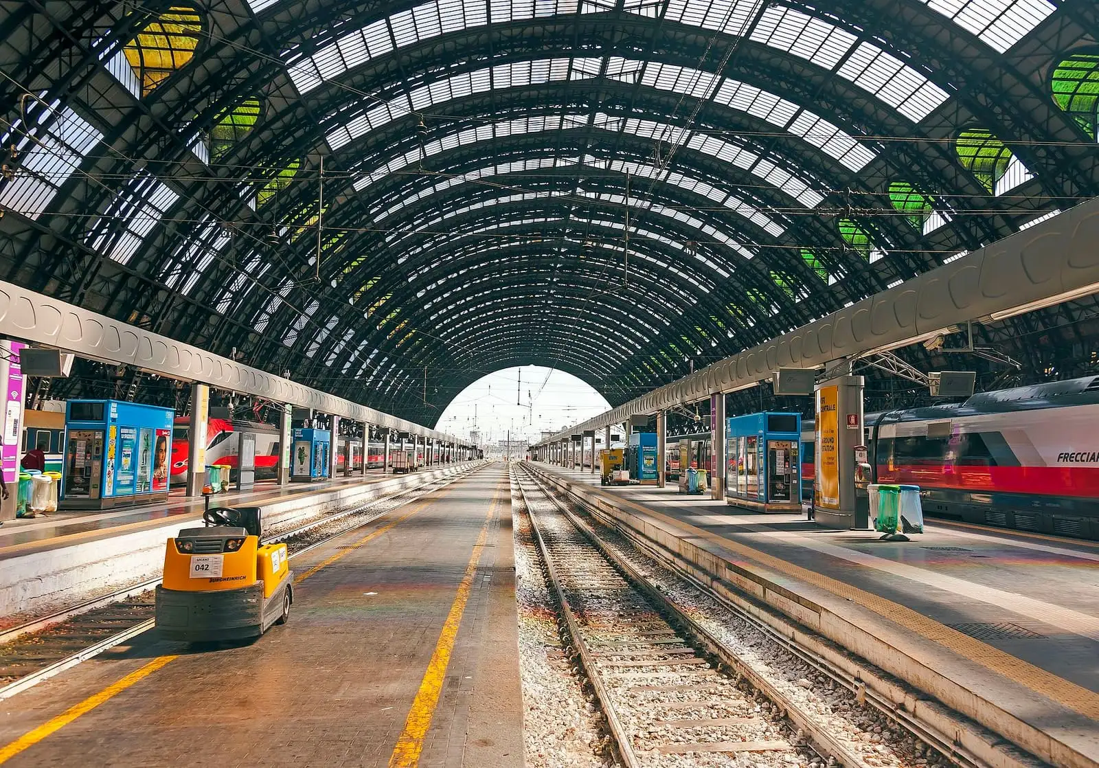 Empty platforms and tracks under the arched iron and glass train shed of Milano Centrale