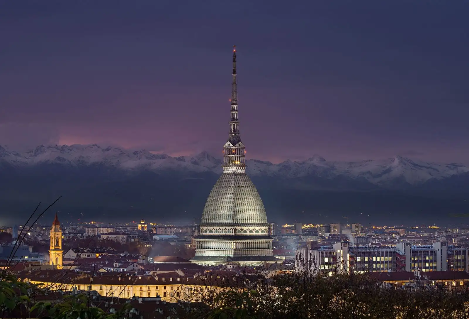 The Mole Antonelliana lit at dusk above Turin, with the snowy Alps behind