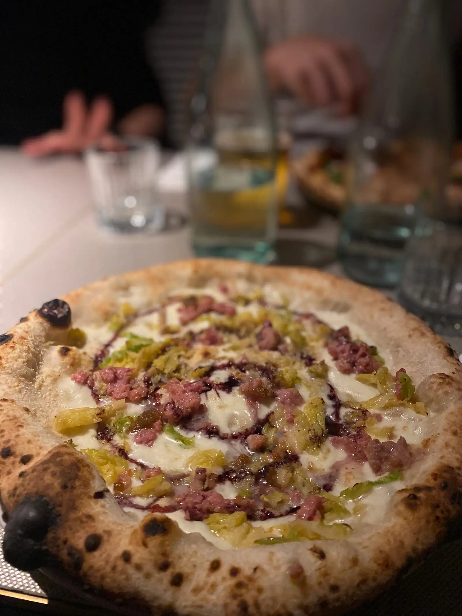 A Neapolitan-style pizza with a puffy charred crust on a restaurant table