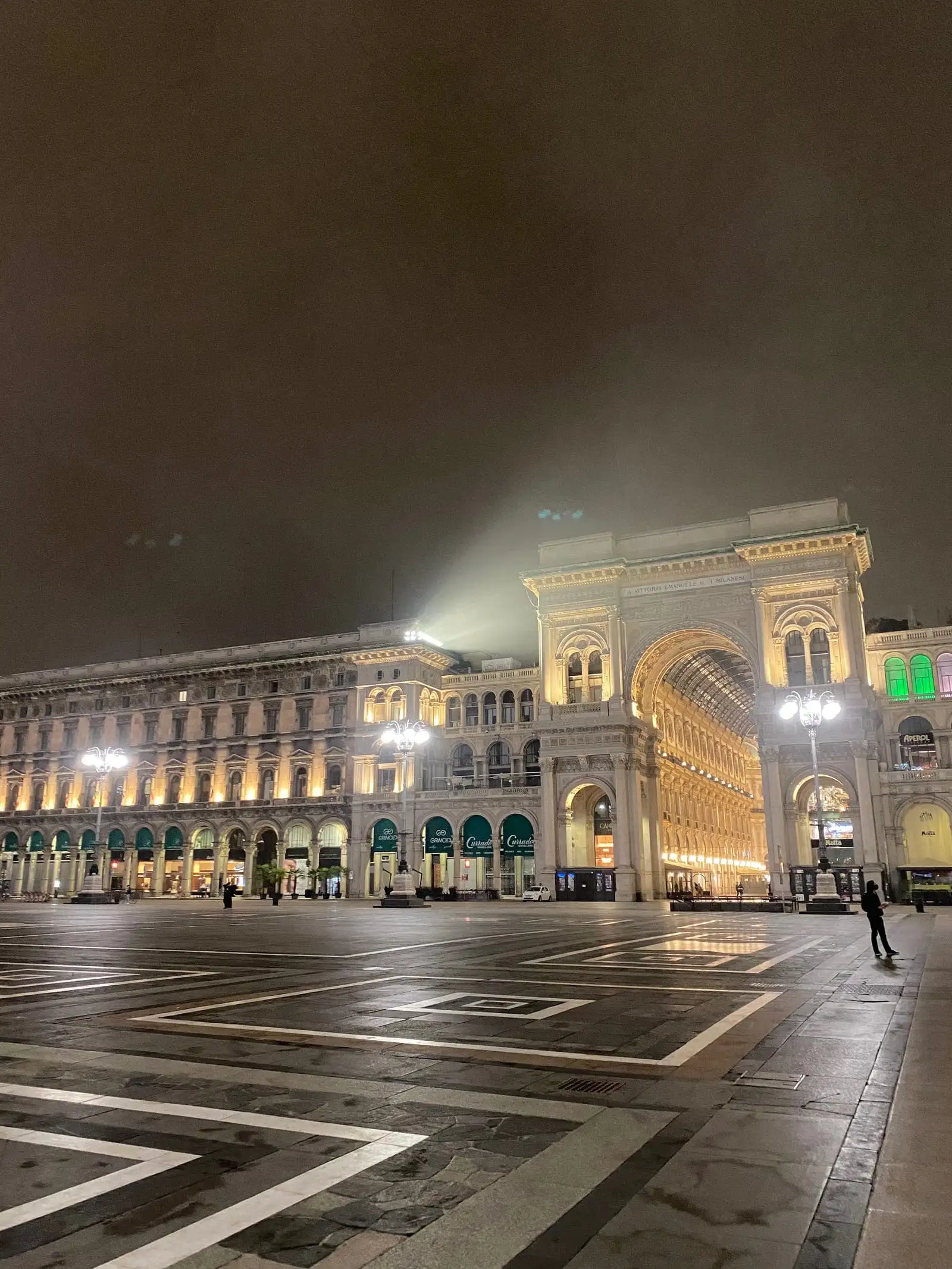 Piazza del Duomo at night with the Galleria entrance glowing on the left