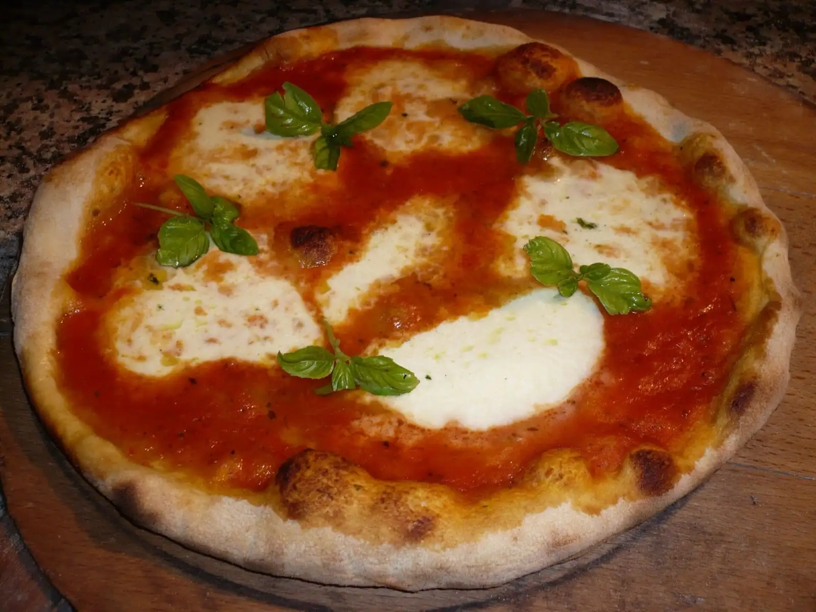 Pizza margherita napoletana con pomodoro, mozzarella e basilico su un tagliere di legno
