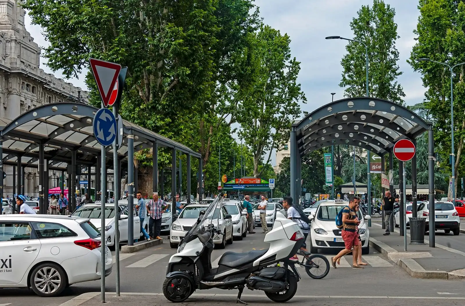 White taxis queuing under the canopies of the taxi rank beside Milano Centrale station