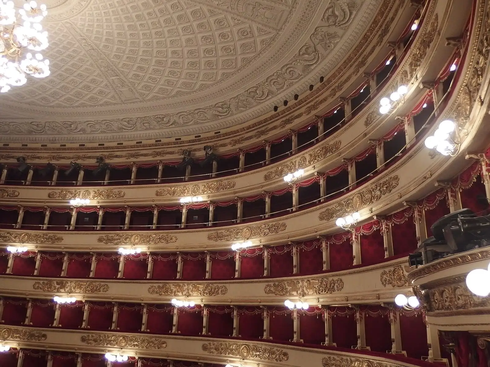 The tiers of gilded boxes with red interiors inside the Teatro alla Scala auditorium, under the domed ceiling