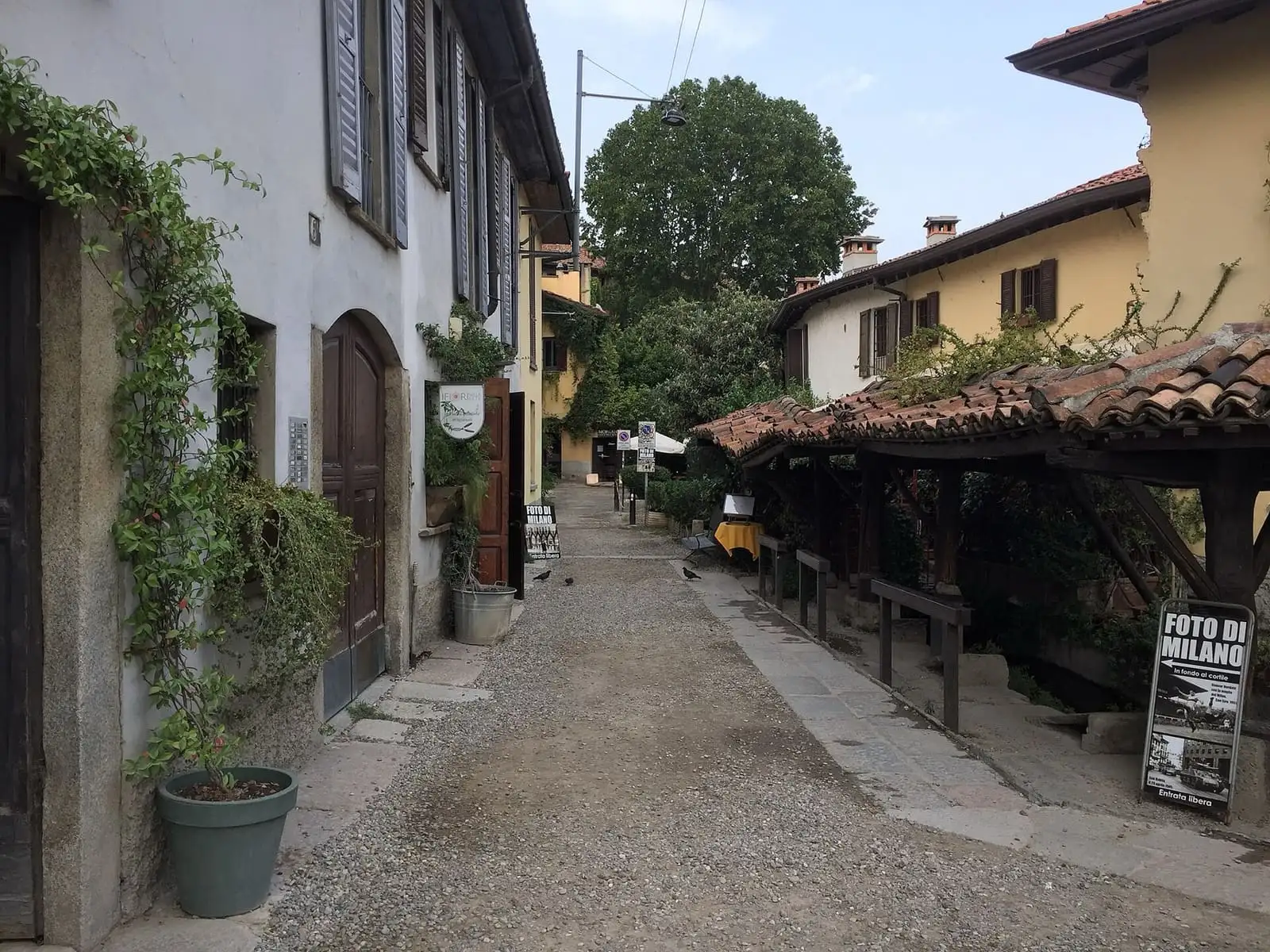 The Vicolo dei Lavandai in Milan, a gravel alley with old houses on the left and the tiled roof over the stone washing stalls on the right